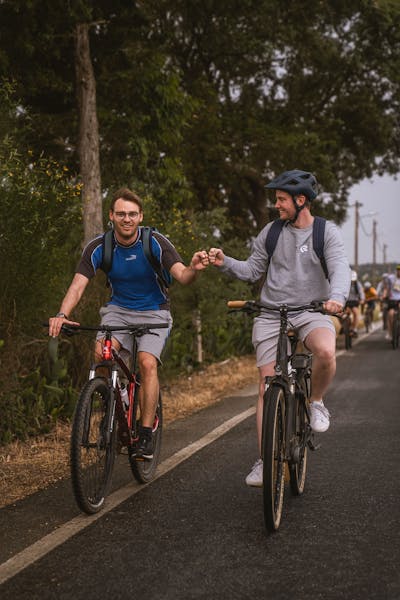 Two Craftzing colleagues on a bike giving each other a fist bumb