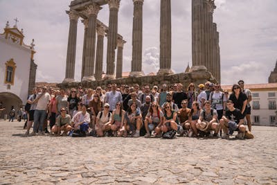 About 60 Craftzing colleagues posing for a picture in a front of an old Roman statue in the city of Evora in Portugal