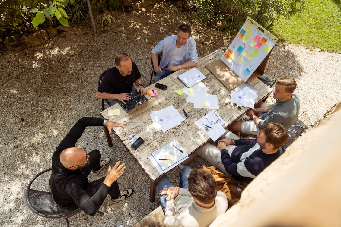 Group of Craftzing colleagues sitting outside around a table, having a workshop