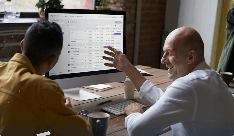 An accountant and its client discussing financial data they see on the screen of an Imac in front of them. The screen shows data on the aiGust platform.