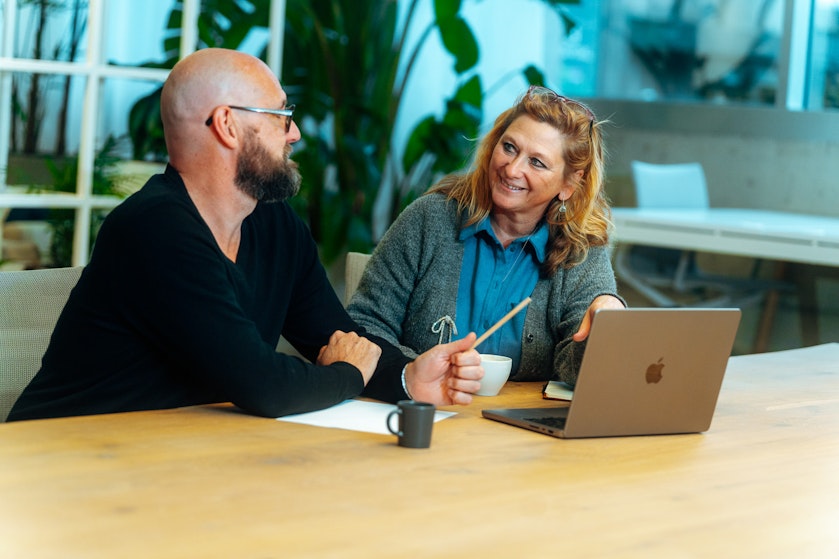 Business Partner Financial Services Hilde Van den Dungen discussing something with her colleague Kenneth Roelandt at a desk in the Craftzing Antwerp office