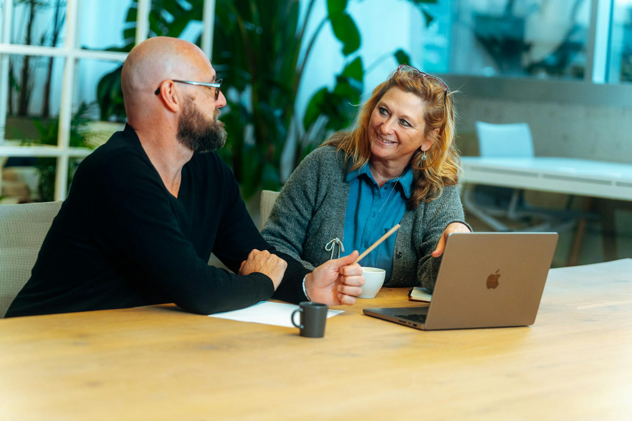 Business Partner Financial Services Hilde Van den Dungen discussing something with her colleague Kenneth Roelandt at a desk in the Craftzing Antwerp office