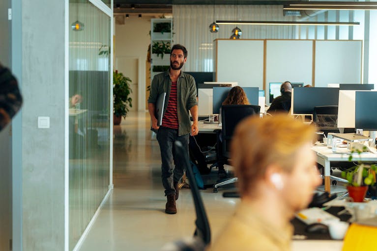 People sitting at their desks and one colleague walking through Craftzing's Antwerp Office