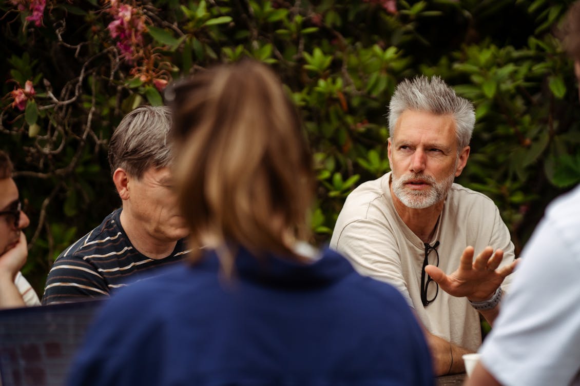 Close-up of a male Craftzing colleague speaking to people seated next to him at the table, whose faces are not visible.