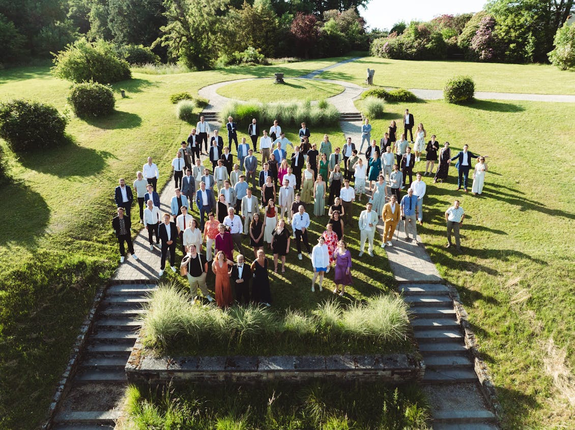 Group picture of all Craftzing colleagues standing on top of a small green hill.