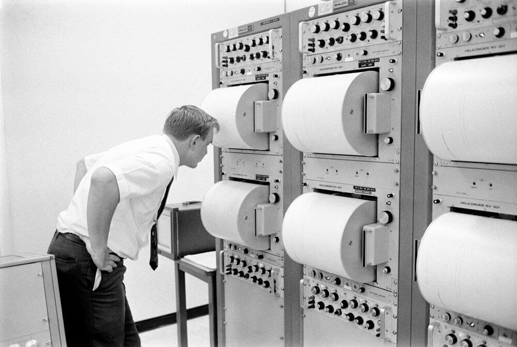 An engineer monitors data in the Mission Control Center Lunar Science Support Room (LSSR) using drum seismometer recorders. Photo courtesy of NASA