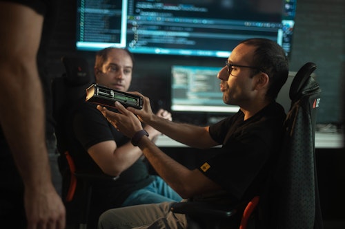 Dewesoft hardware engineers discussing KRYPTON DAQ system electronics with firmware code on the background screens