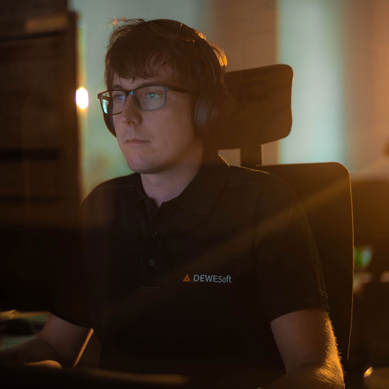 Dewesoft software developer with headphones wearing a Dewesoft shirt