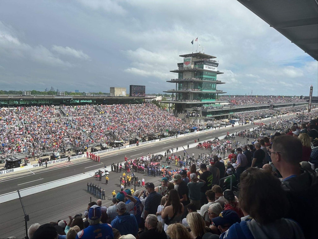 The cars are lined up just before the start of the 108th Indy 500, on May 26, 2024. The pink car visible in the last row was driven by Katherine Legge, who did not finish the race due to a mechanical problem.