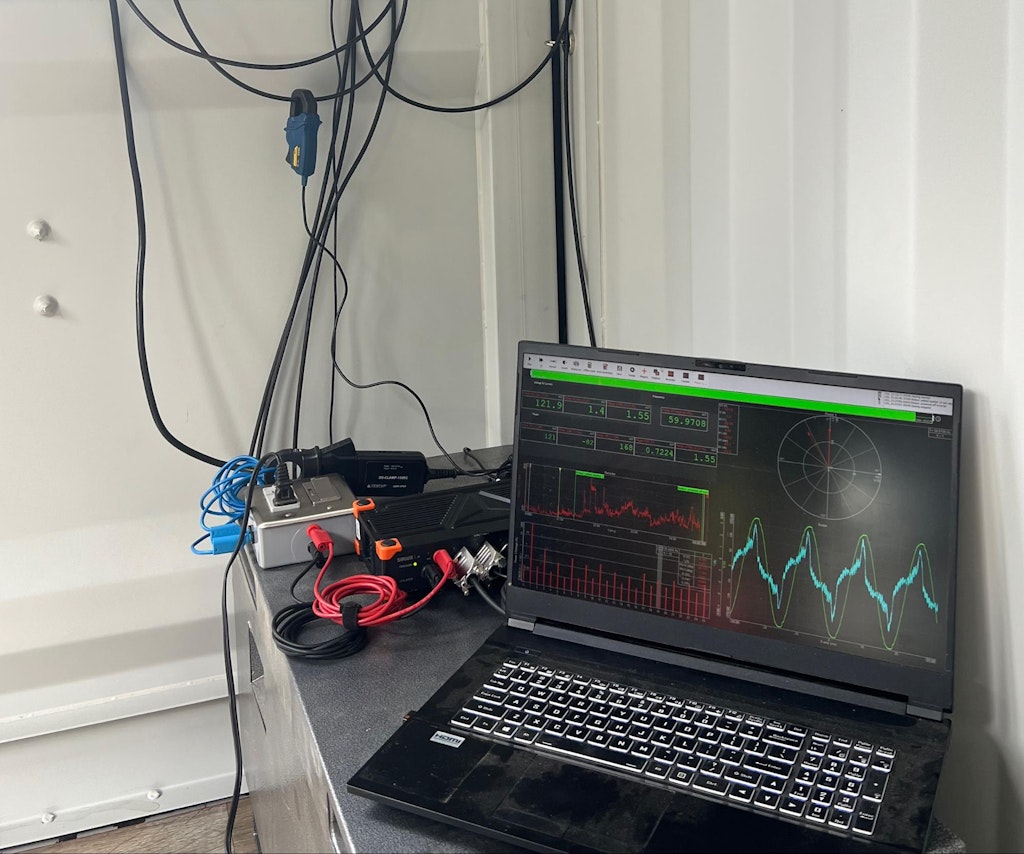 The measurement setup. The SIRIUS slice (black with orange corners) is behind the notebook computer. A current clamp is visible behind the SIRIUS and the silver voltage interface box.