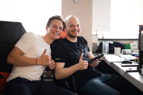 Two Dewesoft student interns holding a PCB and showing thumbs ups