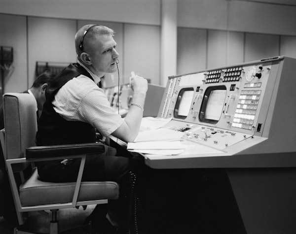 Eugene F. Kranz, director de vuelo, aparece en su consola el 30 de mayo de 1965, en la Sala de Control de Operaciones de la Misión en el Control de la Misión en Houston, preparándose para una misión Gemini-Titan IV: dominio público, NASA Photo S-65-22203.