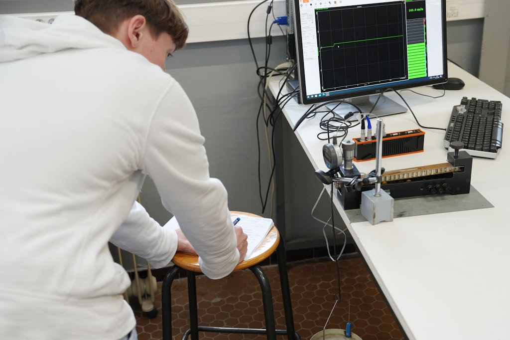 he setup for measuring strain on bending beams. The students apply a load on a cantilever beam, measure the strain, and read the deflection.