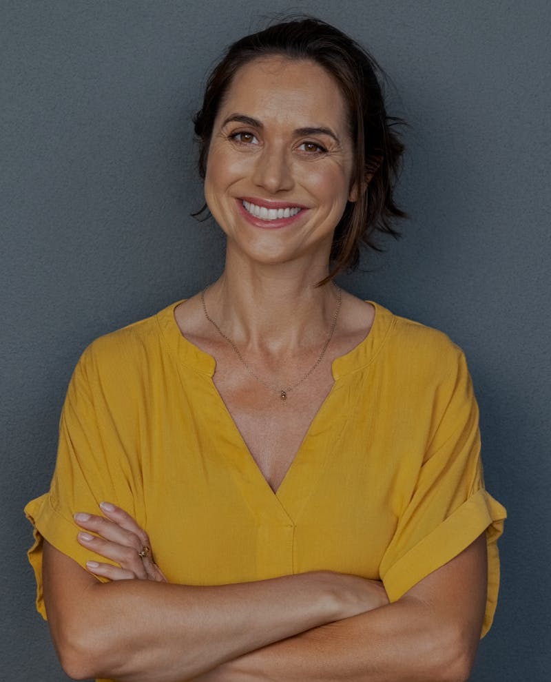 Woman smiling, wearing a yellow top