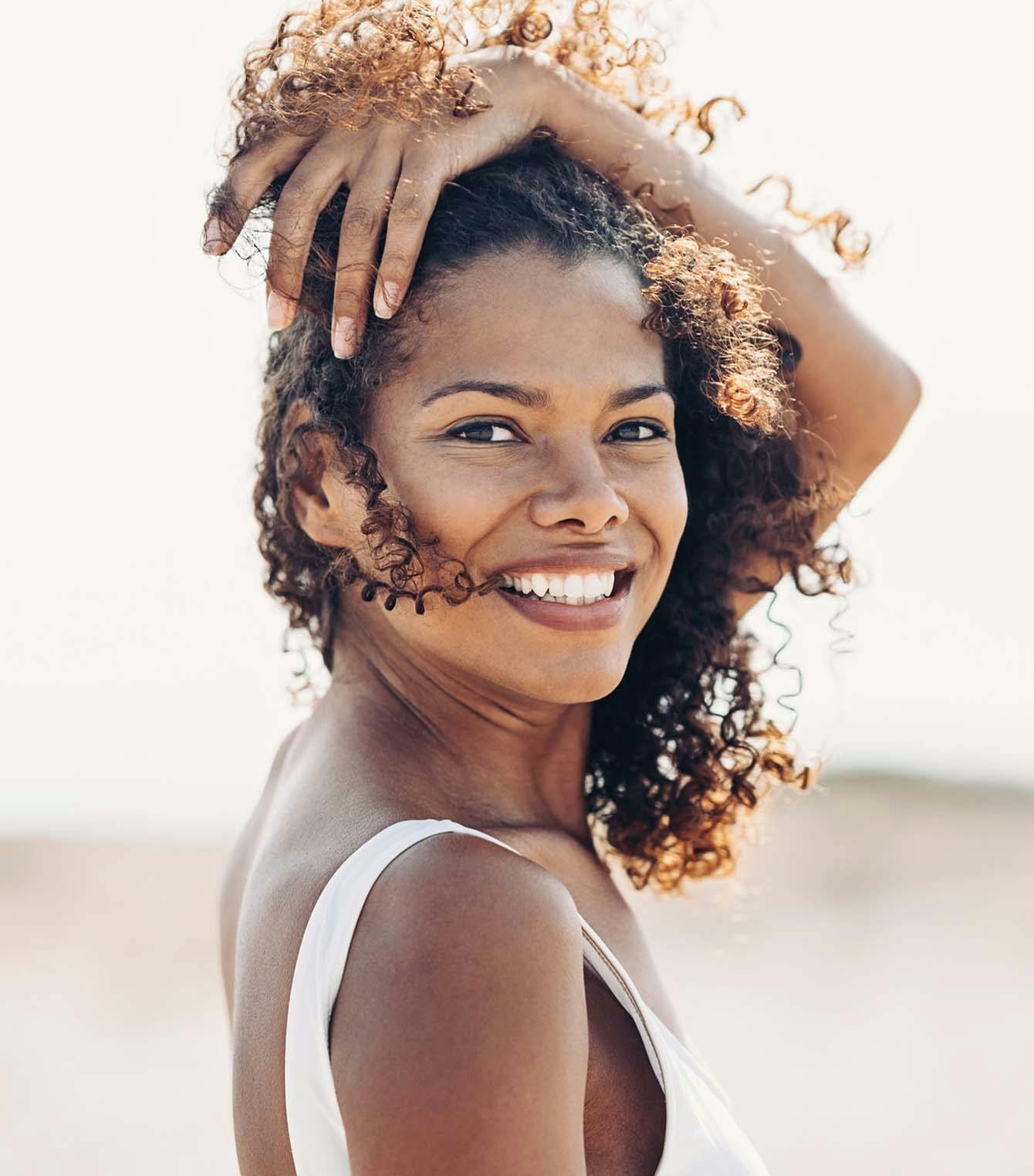 Woman with her hand in her curly hair, smiling