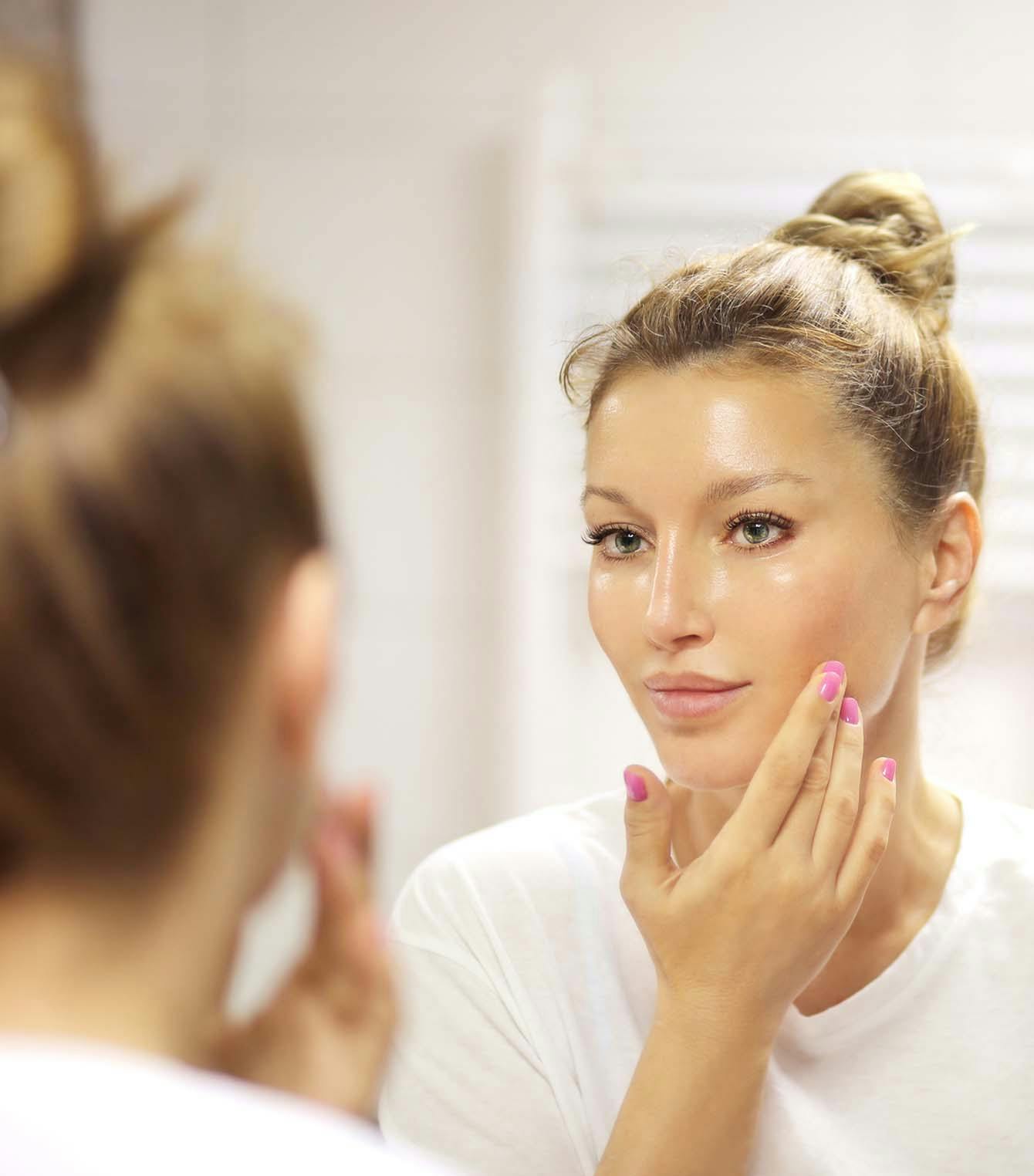 Woman looking in the mirror touching her face
