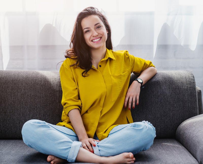 Woman in a Yellow Shirt Sitting on a Couch