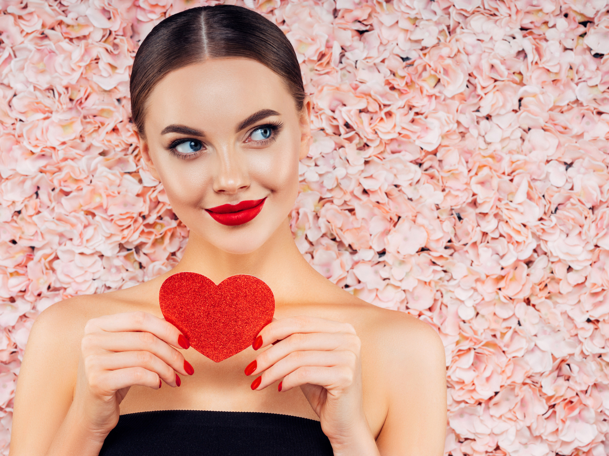 Woman Holding a Little Heart with Pink Roses in the Background