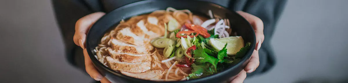 woman's hands holding chilli chicken ramen