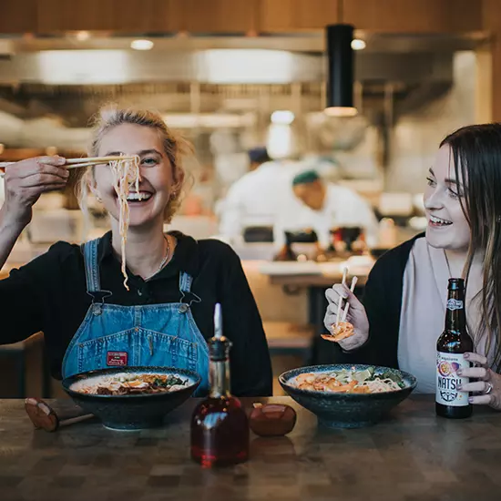 two women eating ramen in a wagamama restaurant