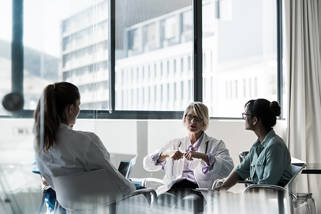 Three doctors in a room consulting while sitting down