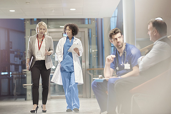 Two doctors conversing in front of a doctor consulting a patient