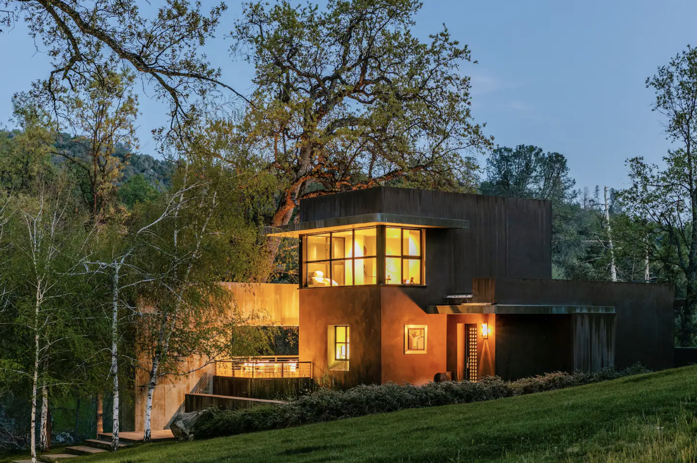 Luxury vacation rental surrounded by trees, grass and mountains.