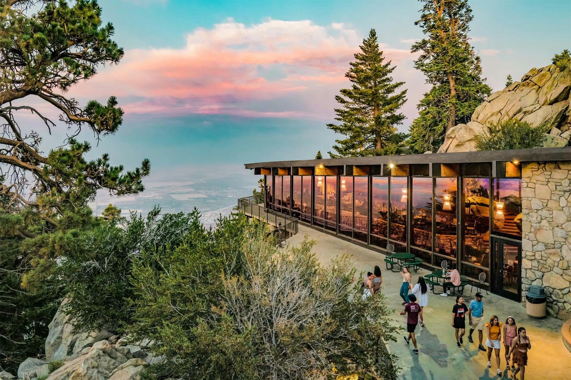A glass and stone building in Palm Springs overlooking the valley with several people on the terrace