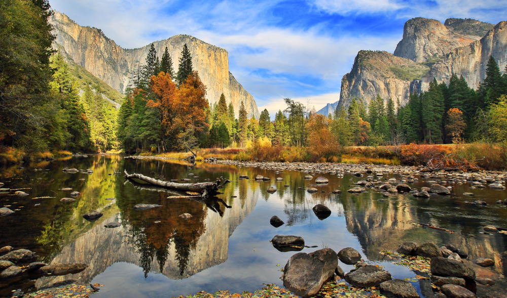 A valley floor with tall rocky mountains and fall foliage.