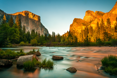 Sunset in the mountains with a river flowing in the foreground.