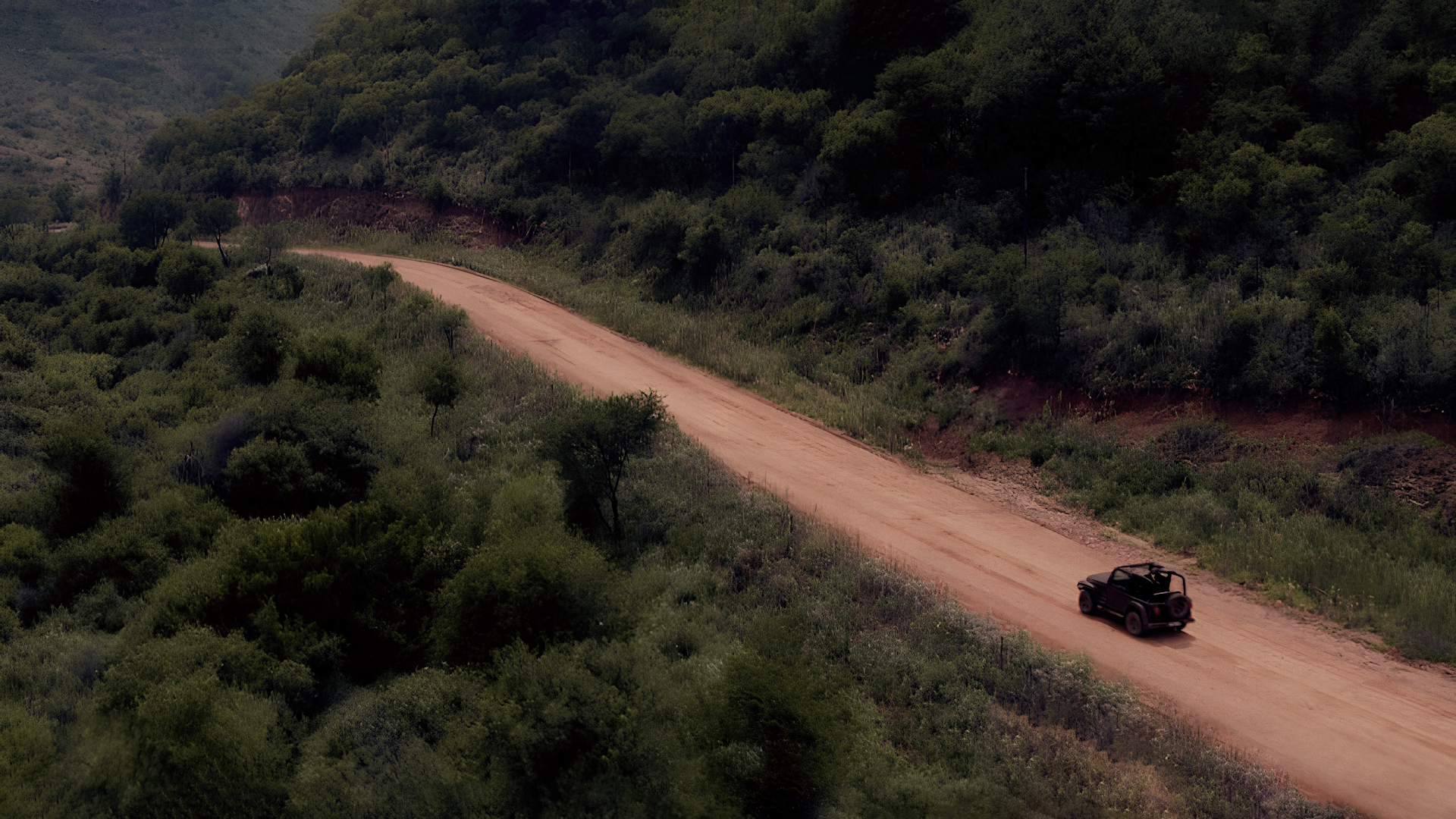 Idris Elba driving through rural Johannesburg flanked by verdant bushes, on his way to see how gold mining has changed.