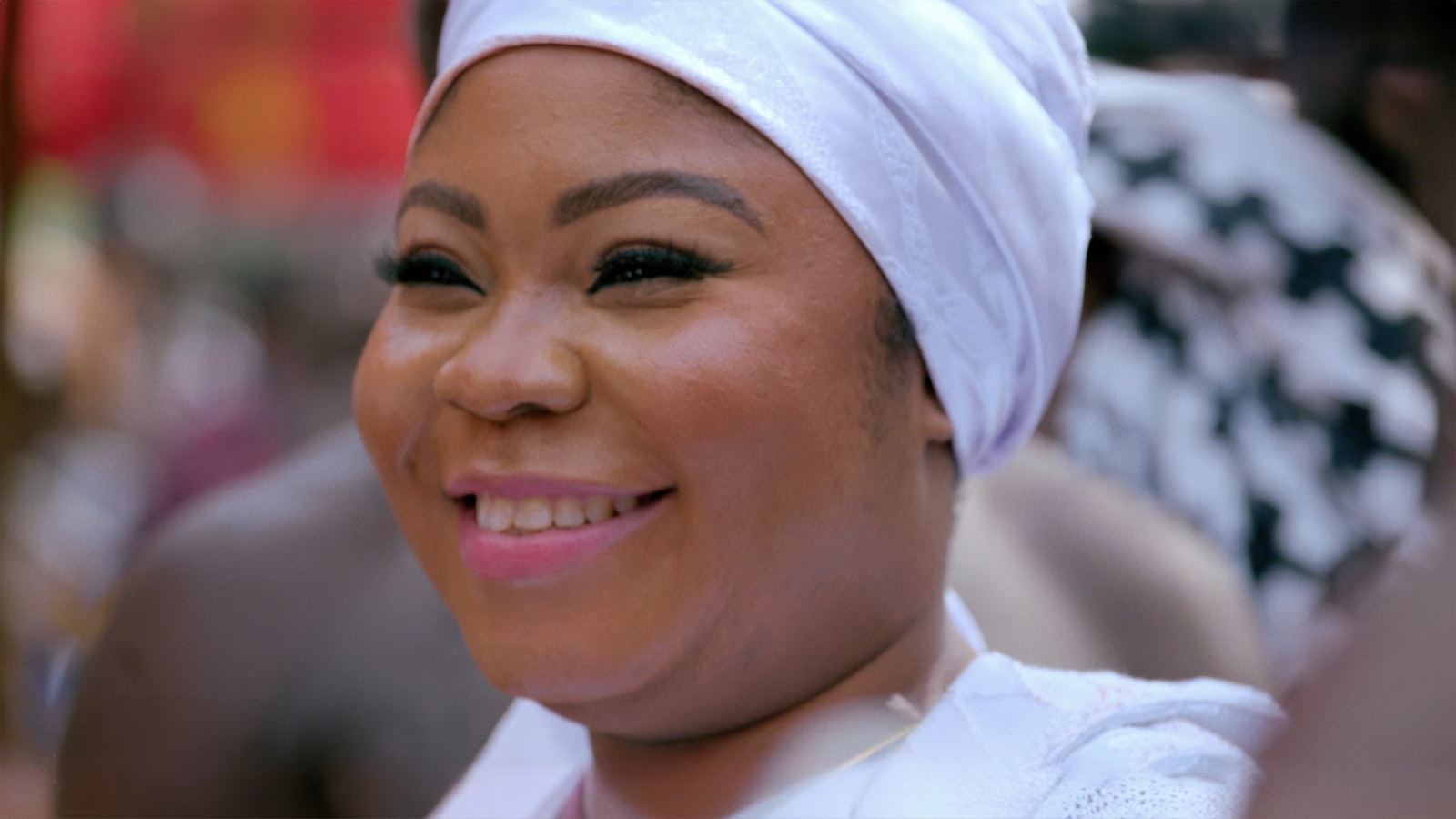 A lady smiles while attending the festival wearing a light lilac headdress and matching dress.