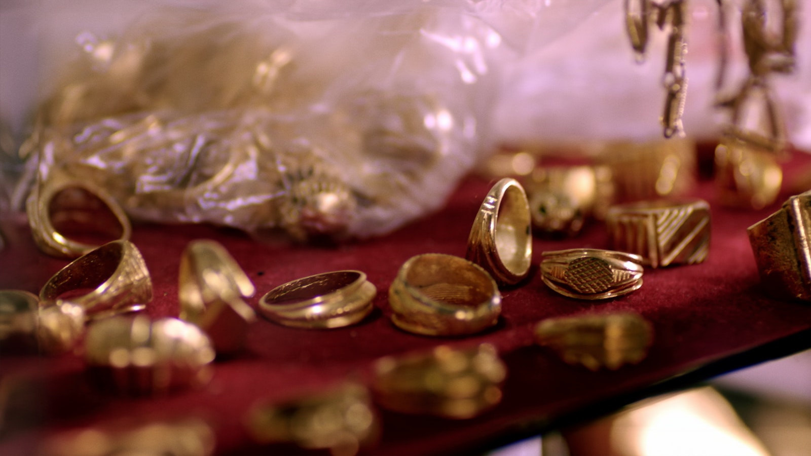 A collection of gold rings sit on a red velvet cloth in the shot of the atelier who dresses Idris Elba.