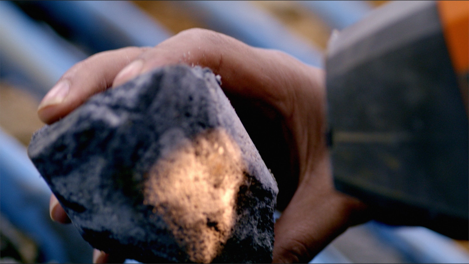 Now in her lab, Denisse Quispe holds a piece of Earth core and fires light at it from a grey-nozzled gun.