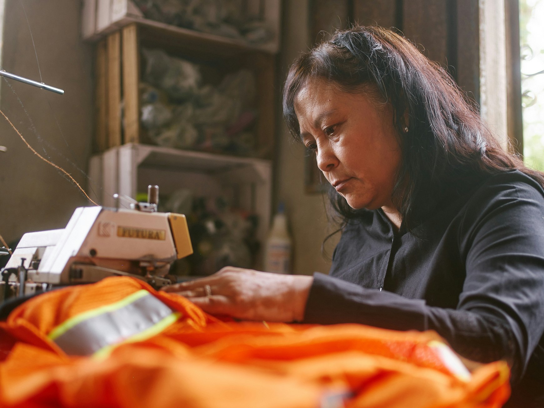 A woman manufacturing high viz clothing for an industrial work place.