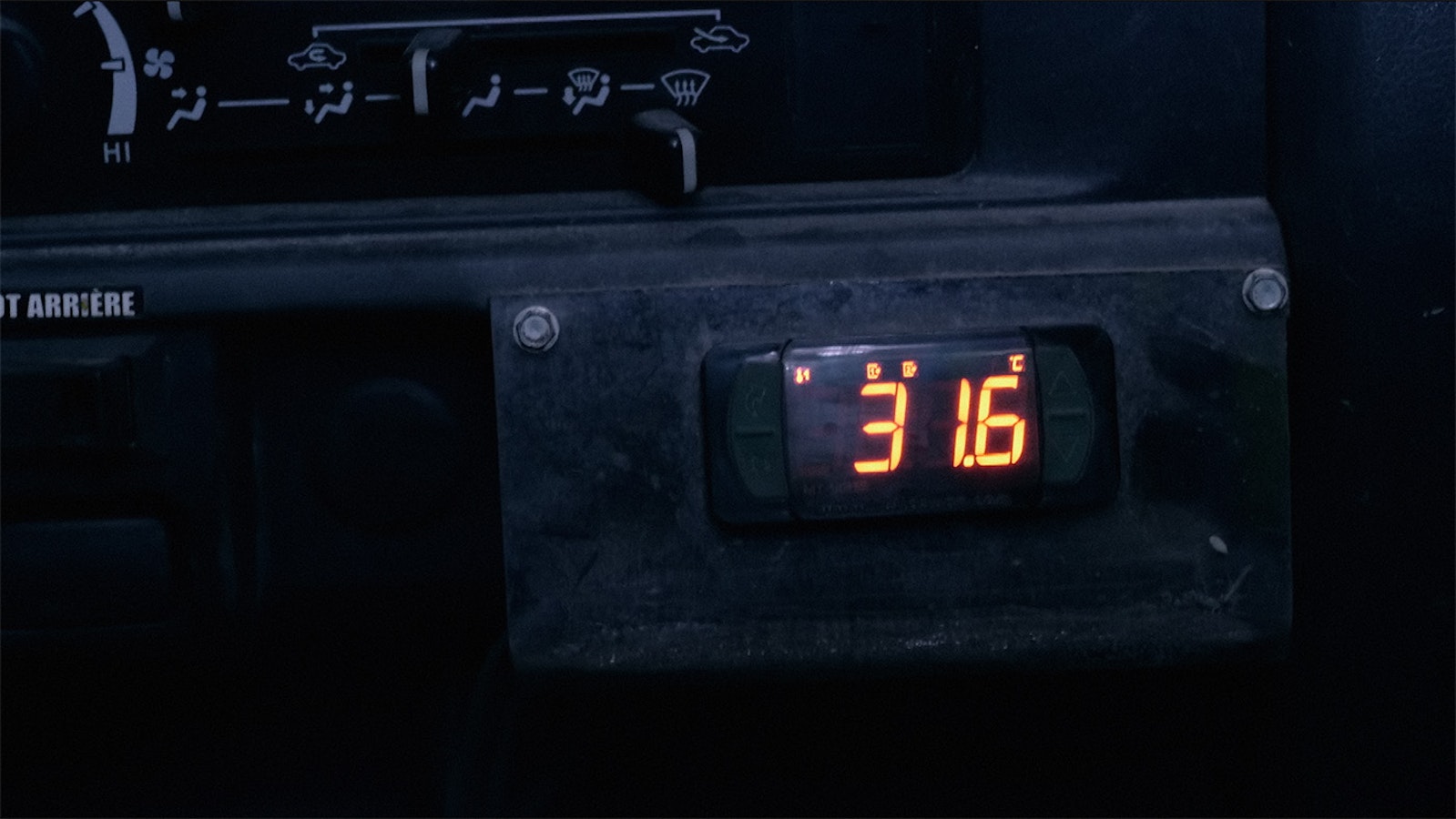 The electronic numbers of the underground mine truck’s thermometer show up in orange light reading 31.6 degrees celsius.
