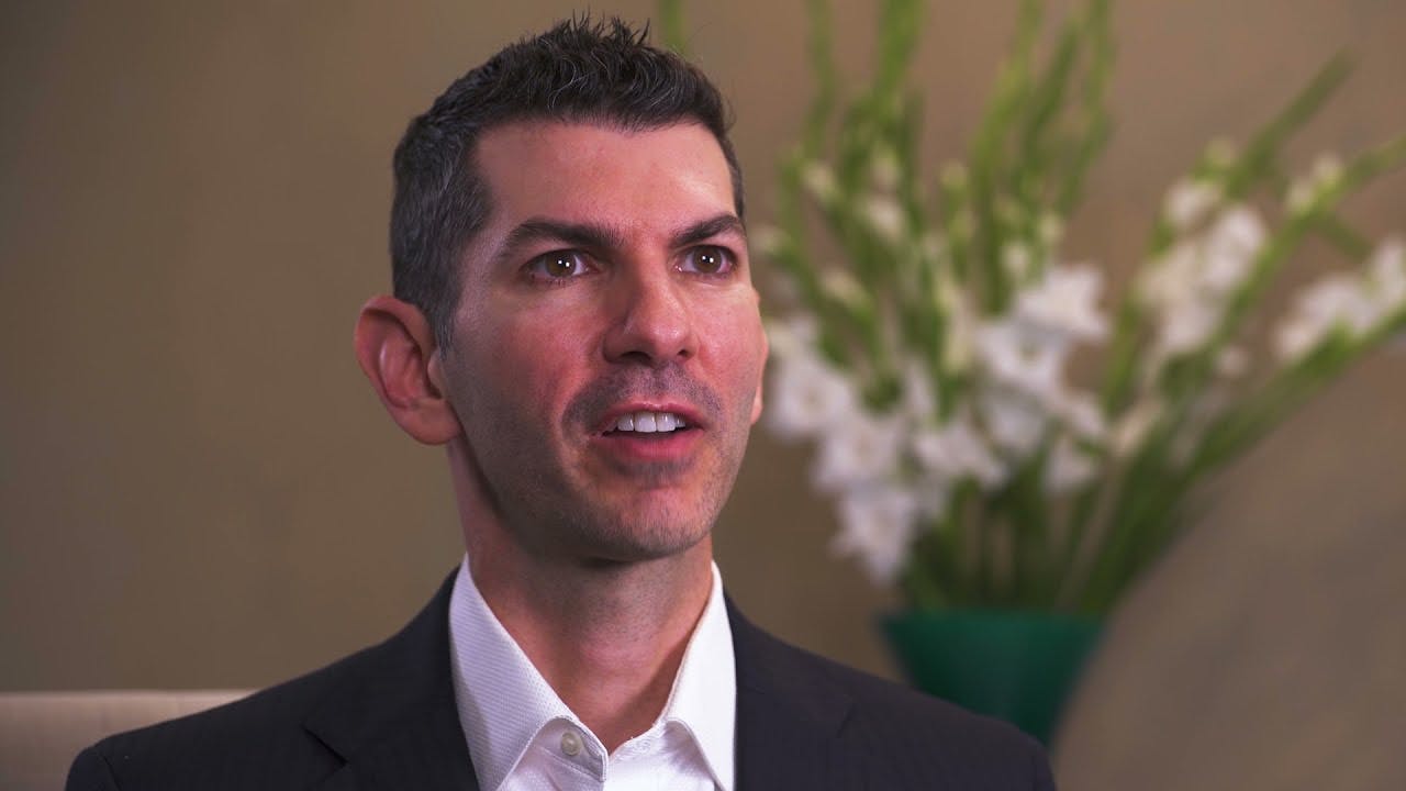 A still of Dr. Cappuccino from a video about hair restoration, wearing a blacl suit