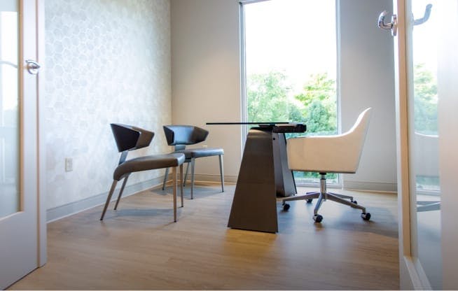 Small office with desk, chairs, and large window