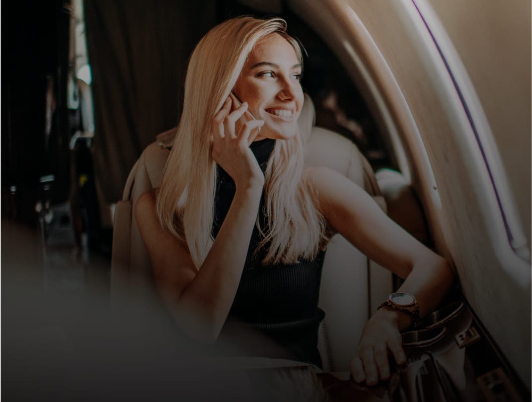 Pretty blonde woman smiling, on a cell phone, looking out an airplane window