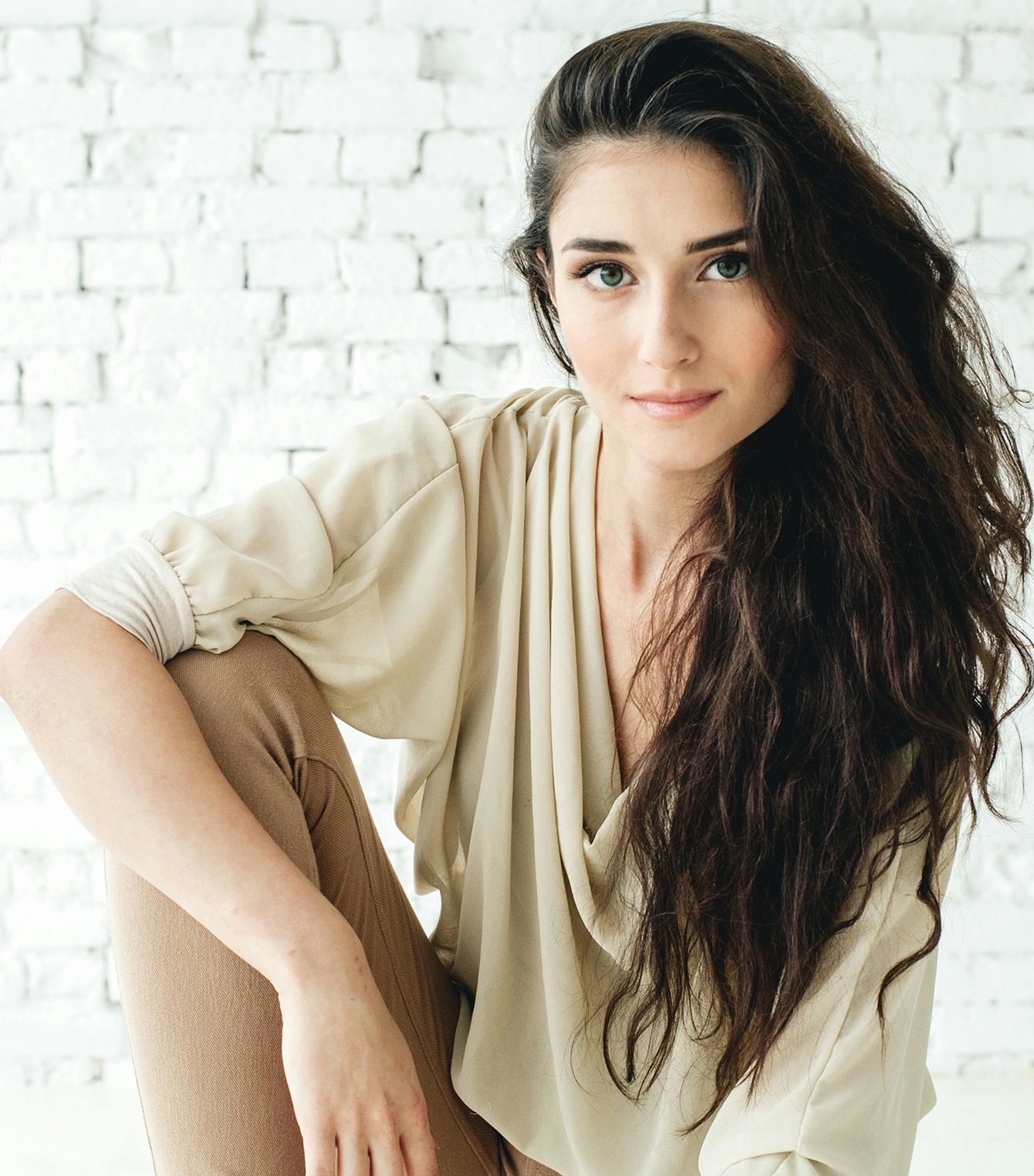 Woman with long brown hair and her arm on her knee