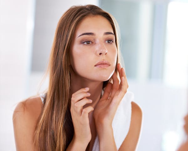 woman observing her skin in mirror