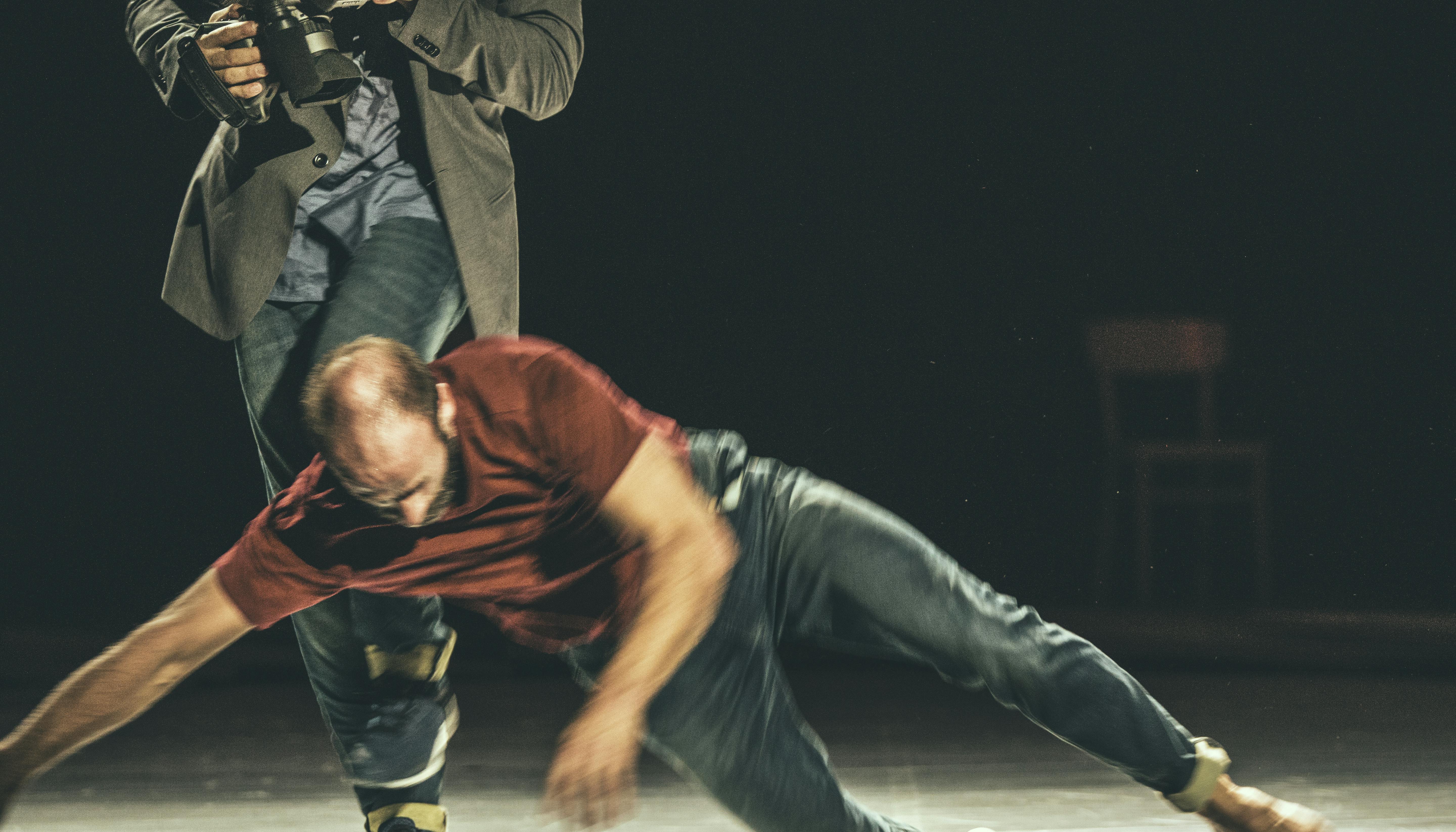 In front, a man is falling to the floor; behind, a second one is moving.