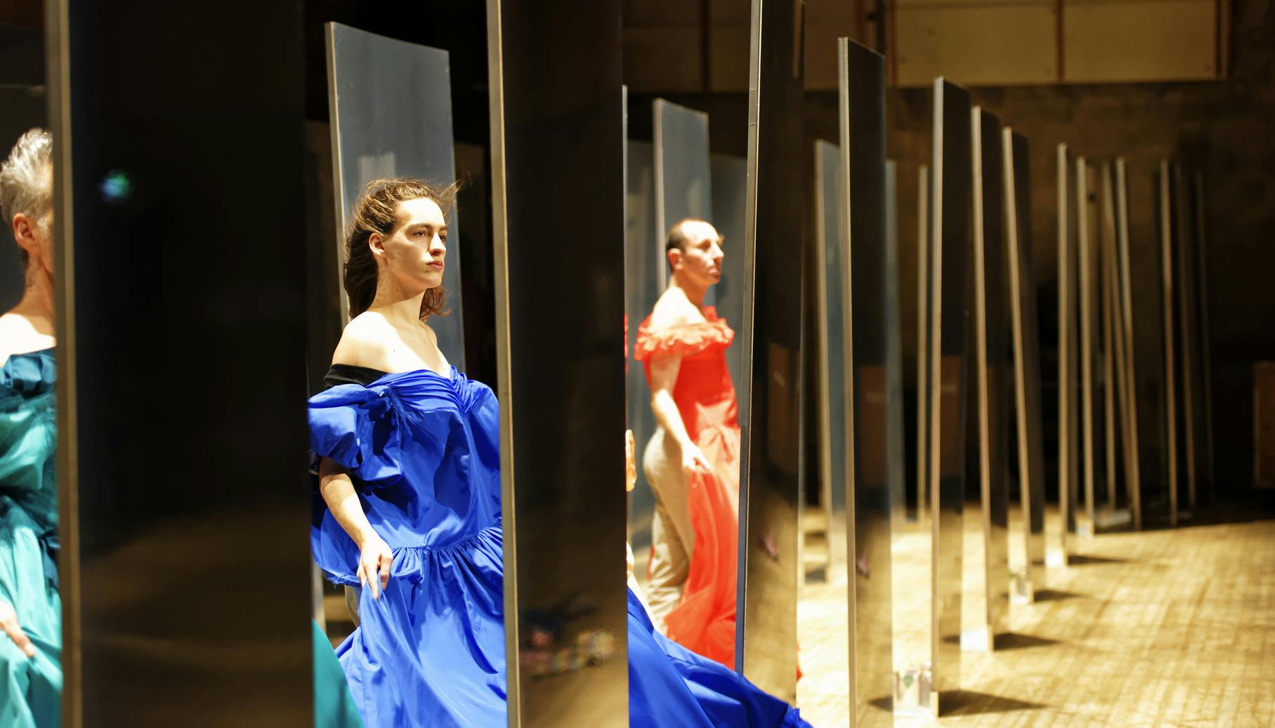On the stage there are dressing rooms, seen from the side, where inside the dancers are standing with their eyes on the spectators and are wearing a ball gown.  