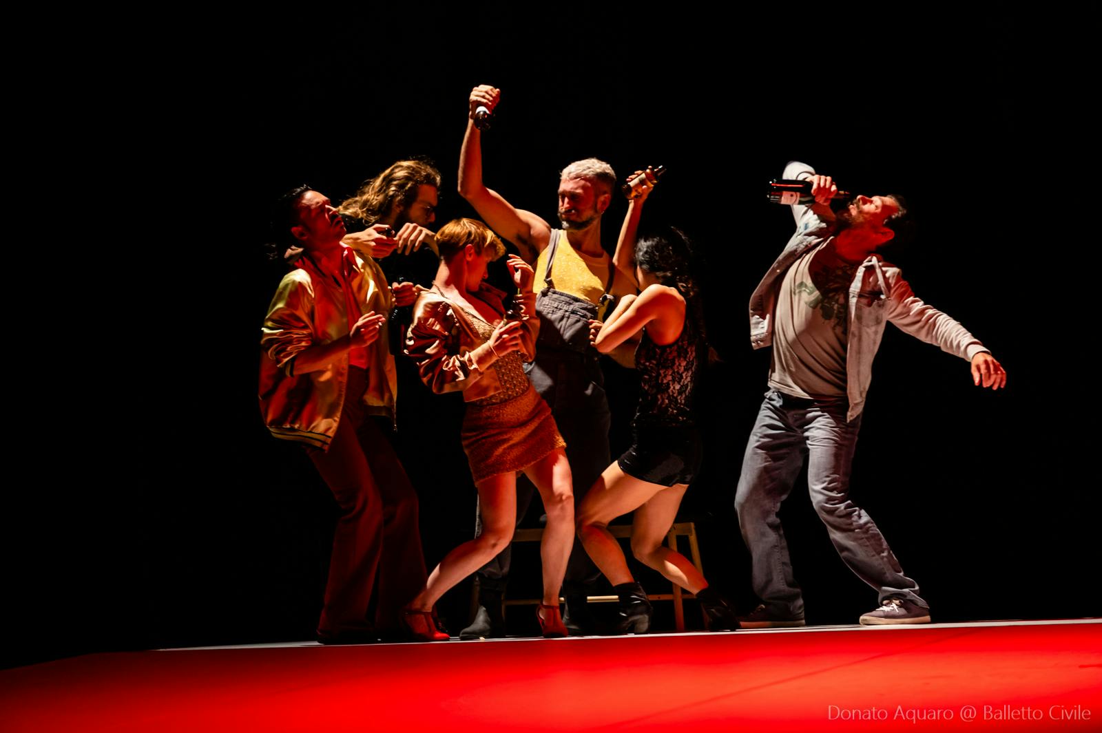 Un gruppo di danzatori misti balla in modo disordinato sul palcoscenico.