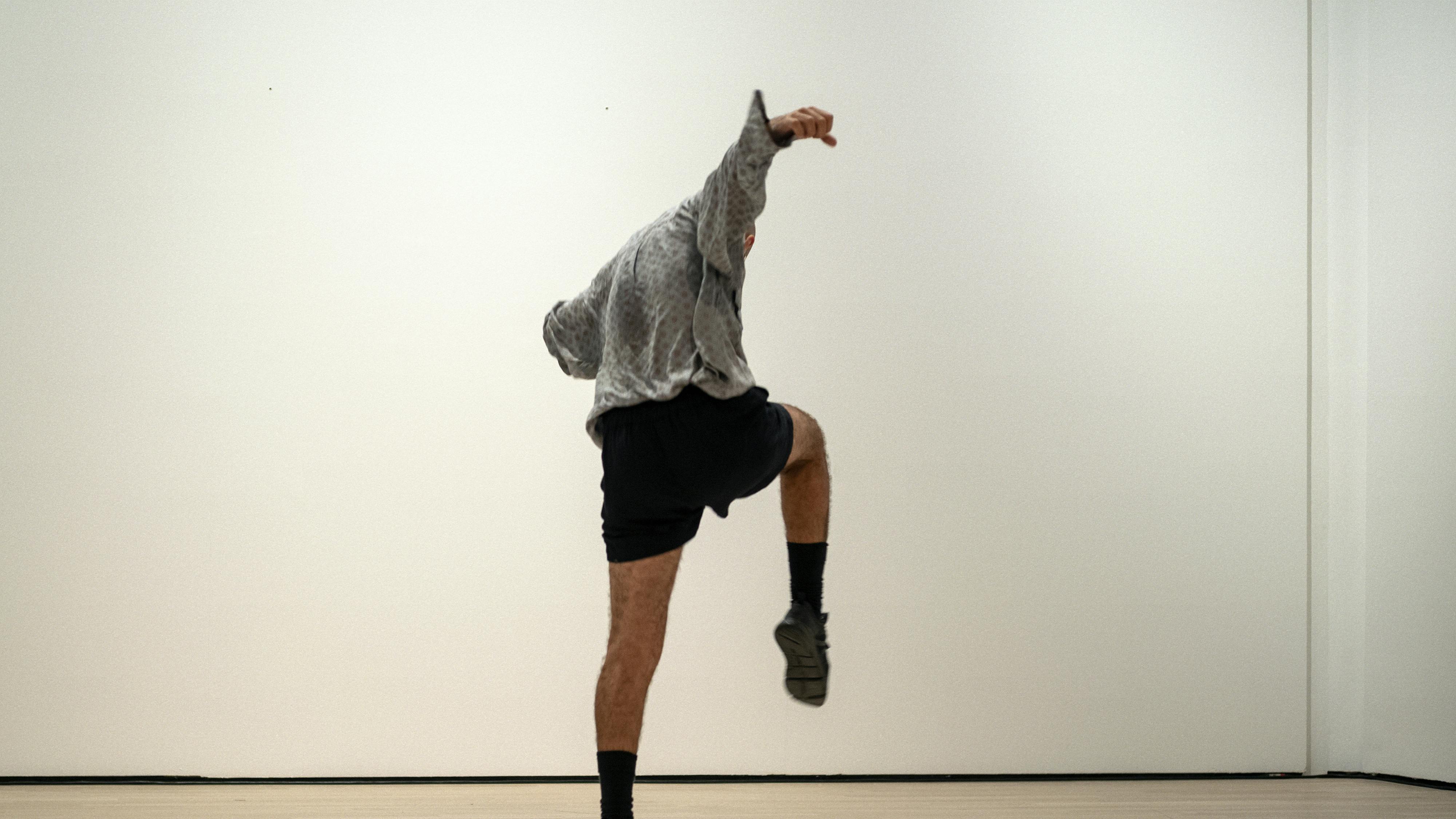 Daniele Ninarello with his back turned, right  leg and arm rised upward. His hand is closed into a fist.