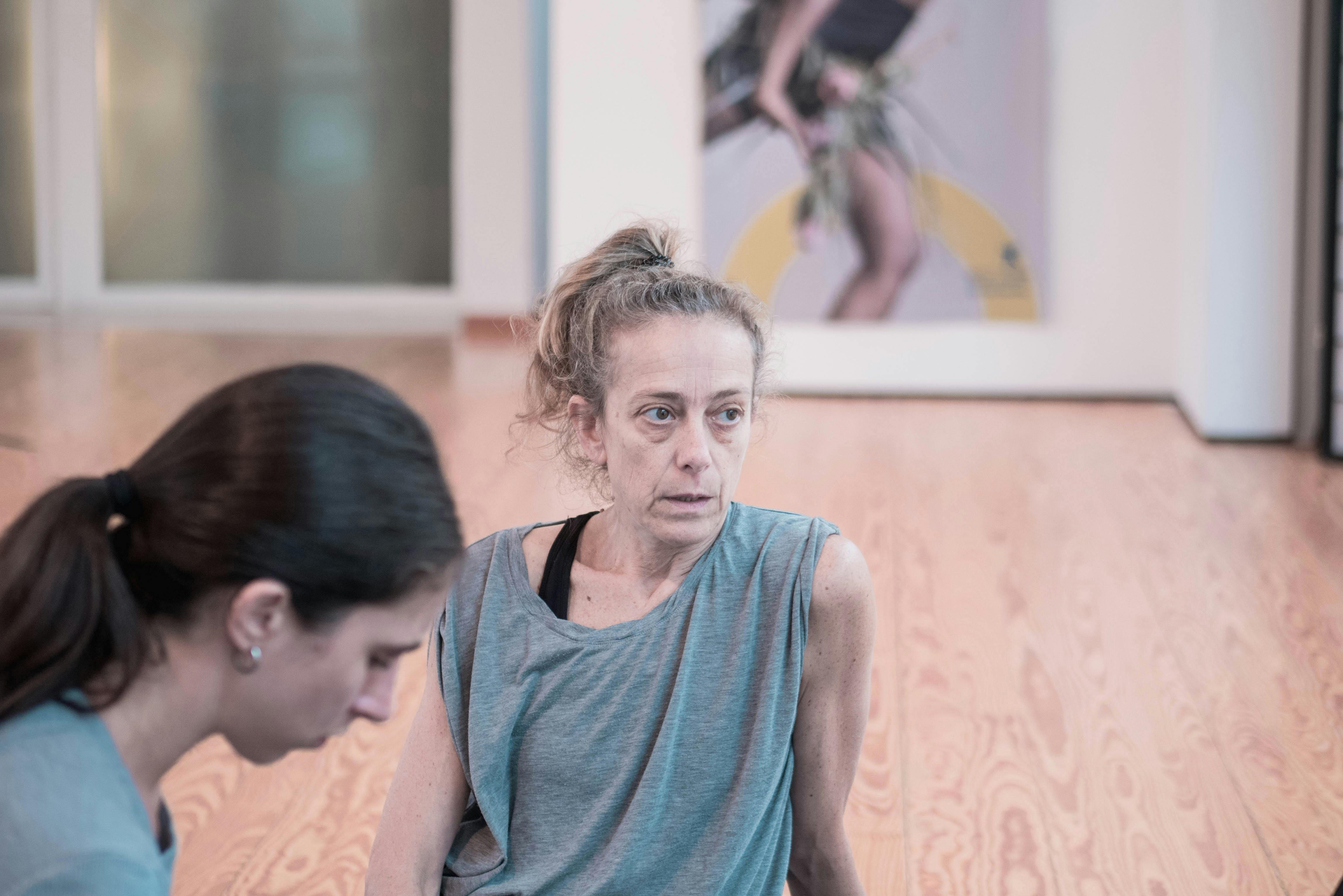 La coreografa Cristina Kristal Rizzo al lavoro nello Studio e parla con i danzatori. Accanto a lei una danzatrice ascolta.