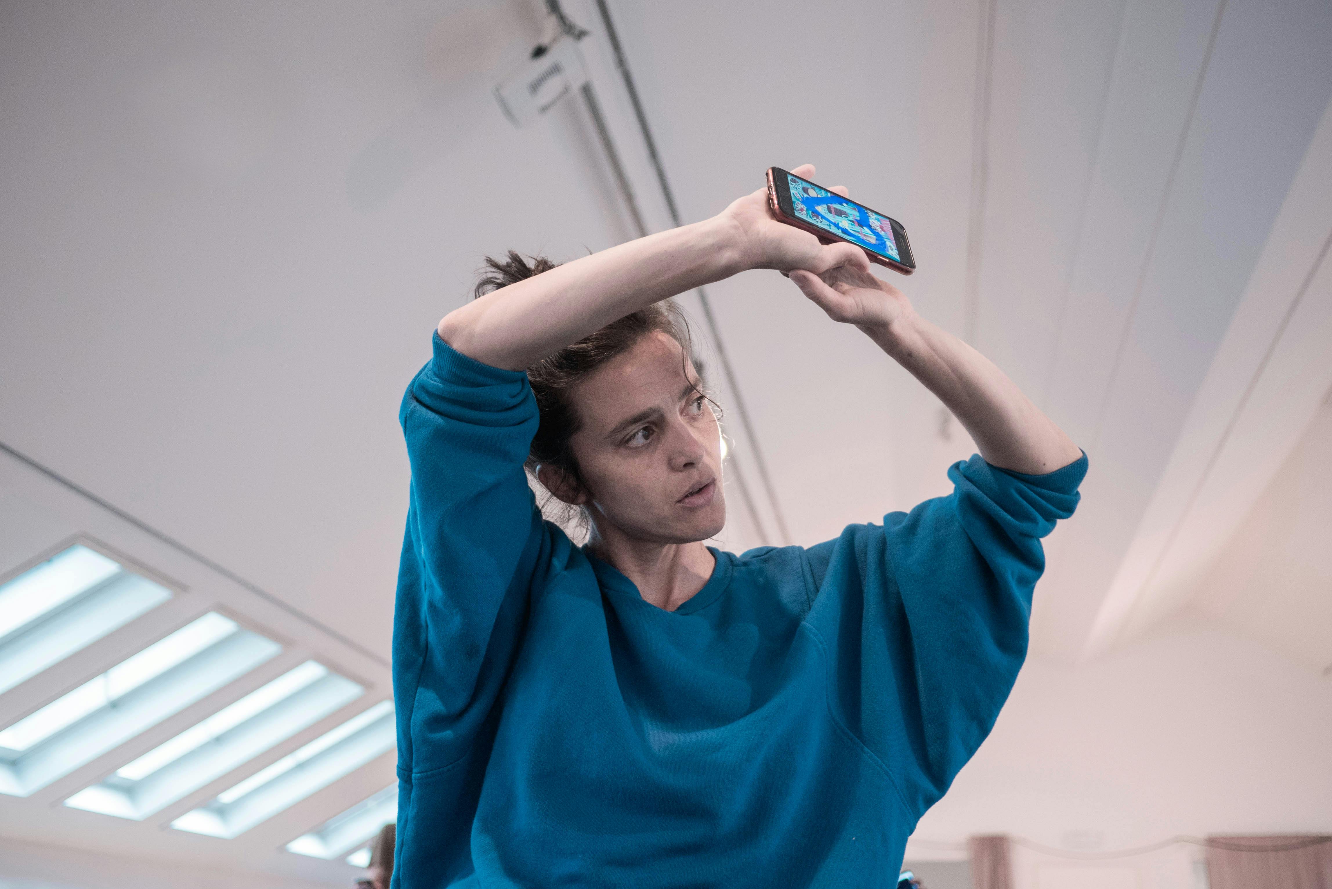 Annamaria Ajmone, dancer and choreographer, raises her arms high, joining her hands in the air.