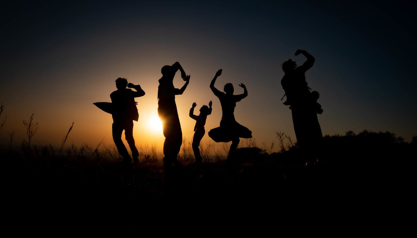 At sunset, five dancers are dancing in various poses against the light.
