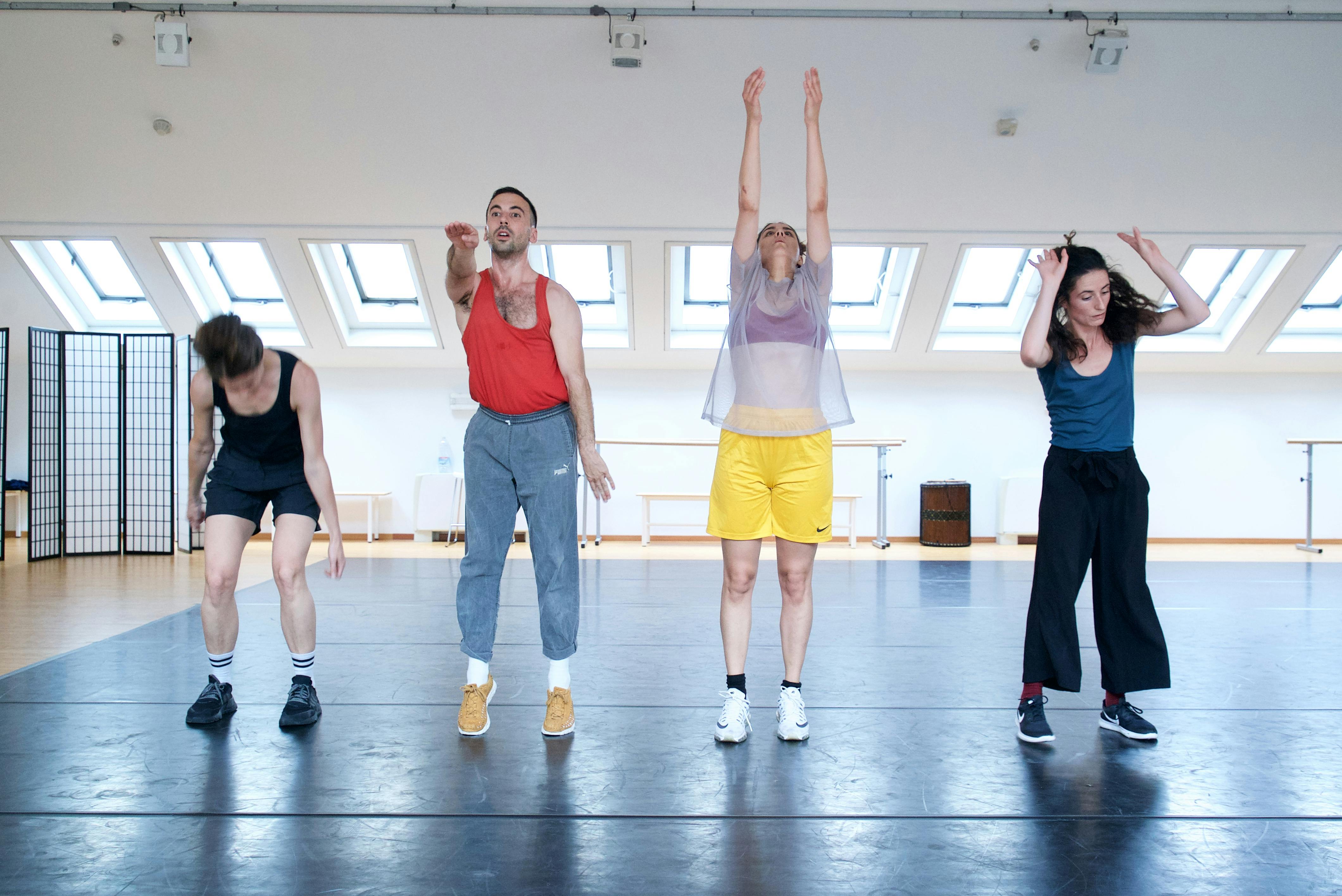 Four performers in a horizontal row in the Studio make different movements with their arms
