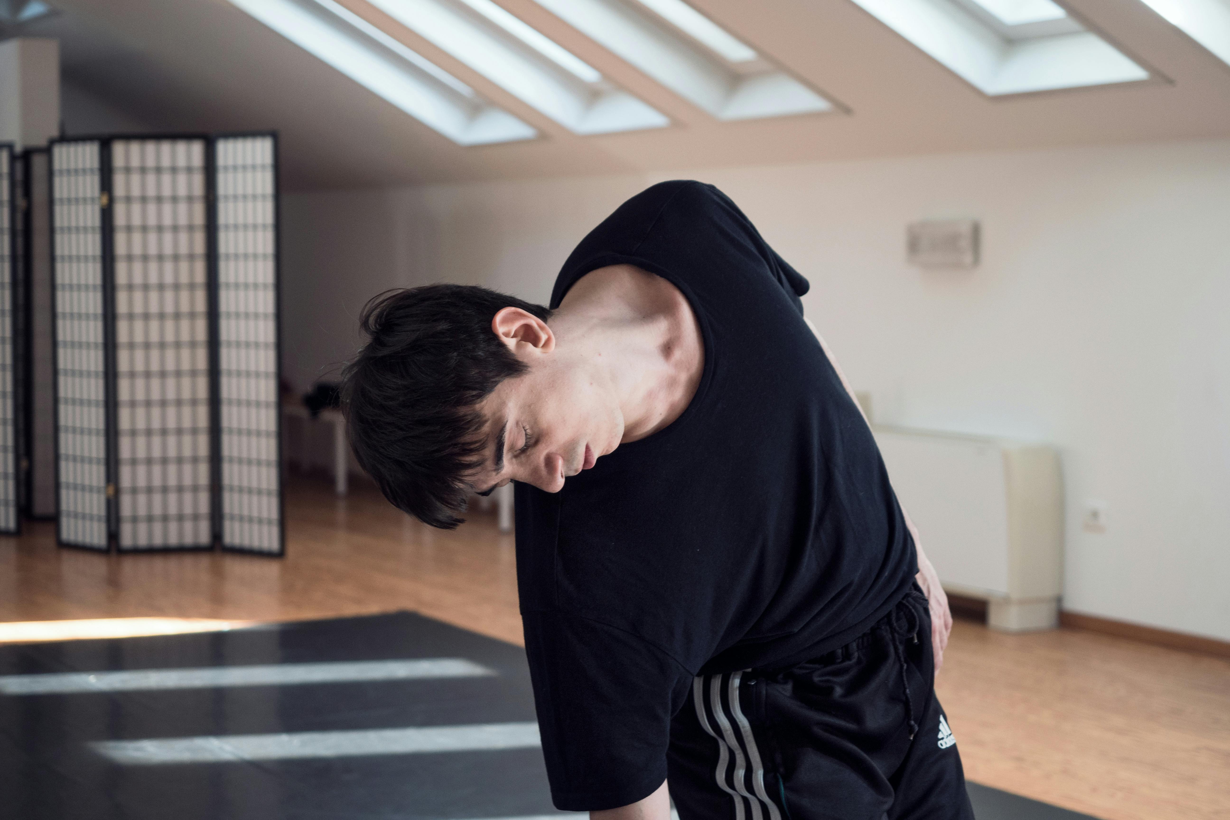 The dancer Cristian Cucco during the rehearsals of Alexis 2.0. Only the upper part of his body is visible, slightly reclined downwards to the right.